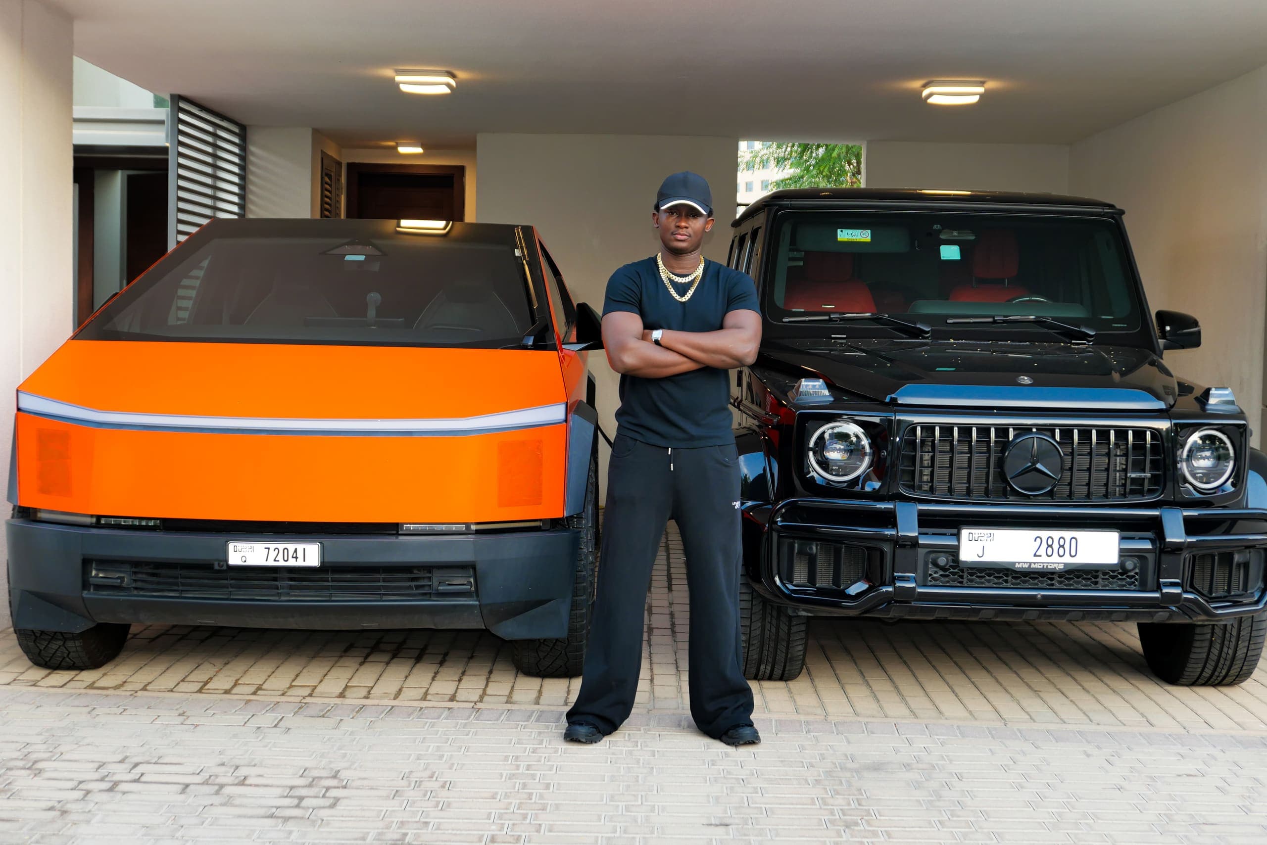 KojoForex at 09:00 GMT, done for the day, standing between an orange Cybertruck and a black G-Wagon